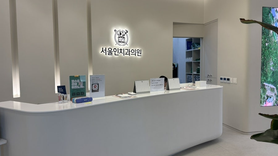 서울인치과의원 로고가 있는 밝은 화이트 데스크와 로비